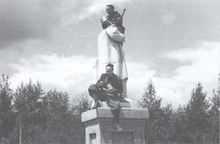 在被“斬首”的史達林雕像旁吃午飯的兩名黒衫軍士兵。