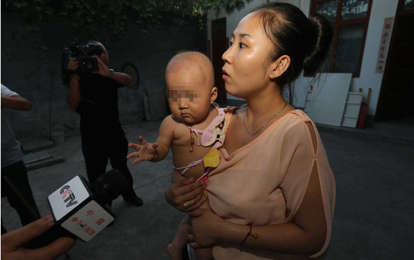懷抱受傷女嬰接受記者採訪