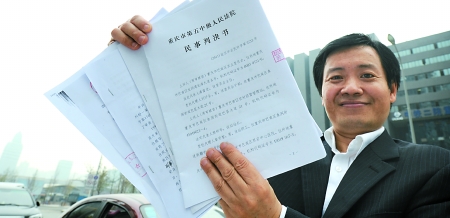 周榮焱在向記者展示法院判決書