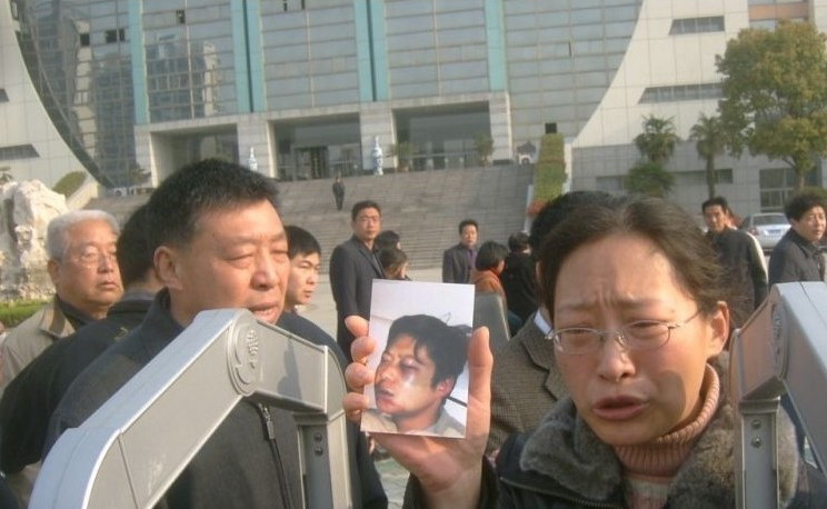 郭艷東妻子舉著丈夫被打後拍的照片