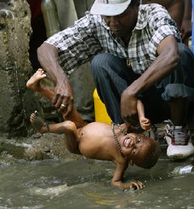 一位信徒為他的孩子泥浴祈福