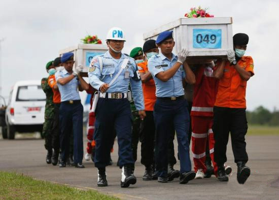 搜救人員將裝有遇難者遺體的棺材抬上運輸機