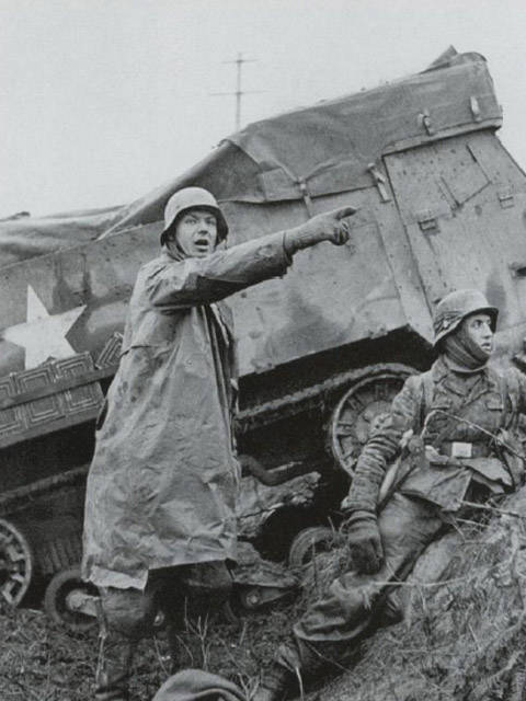 一名德軍在被擊毀M3旁打出前進的手勢