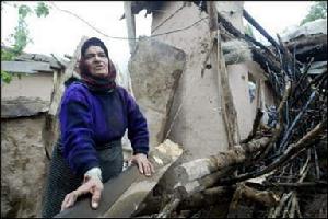 一名伊朗婦女站在地震中被毀的房屋前