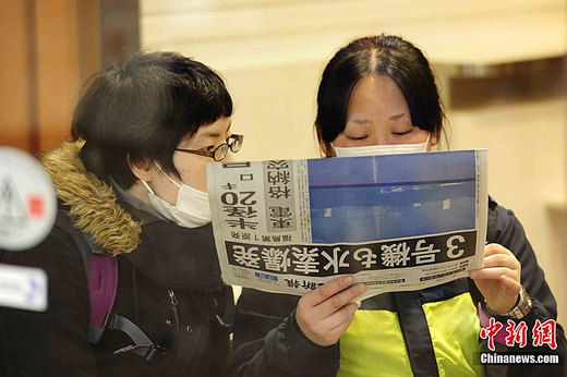人們通過報紙瀏覽日本地震情況